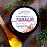 Coconut Dreams Skincare Frankincense Rescue Butter tin with evergreen sprigs and wooden spoon.