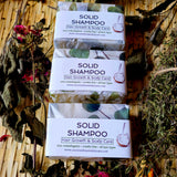 Coconut Dreams Skincare solid shampoo bars wrapped in paper packaging, arranged on woven surface with dried botanicals.