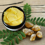 Open jar of Frankincense Rescue Butter showing whipped yellow butter texture with botanical elements.